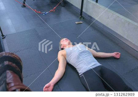 Sportsman resting laying on mat close eyes after myofascial stretching in gym. 131262989