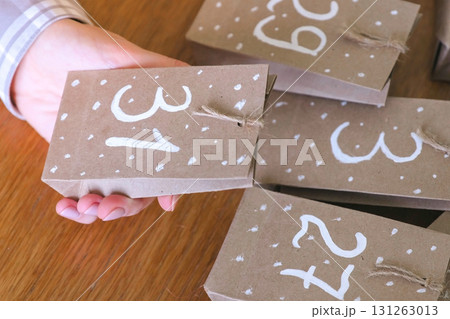 Bags for christmas advent calendar from kraft paper in woman's hand. Bags for christmas advent calendar from kraft paper in woman's hand. 131263013