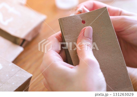 Woman makes a bag for christmas advent calendar from kraft paper. Woman makes a bag for christmas advent calendar from kraft paper. 131263029
