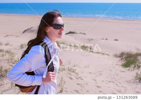 Woman traveller with backpack is looking around in sea sand beach on vacation. Woman traveller with backpack is looking around in sea sand beach on vacation. 131263089