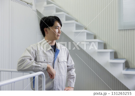 倉庫で台車を押す作業着の男性 131263255