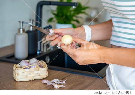 Female hands peeling Chinese single clove garlic on kitchen countertop. Cooking process, natural seasoning, and preparation of fresh ingredient. Female hands peeling Chinese single clove garlic on kitchen countertop. Cooking process, natural seasoning, and preparation of fresh ingredient. 131263493
