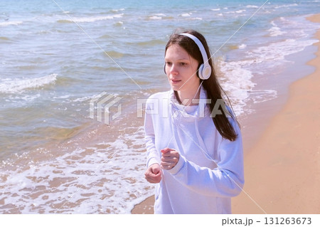 Girl in headphones music jogging at sea sand beach sport run outdoor training. 131263673