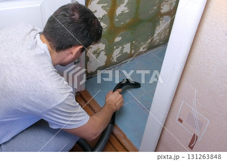 Man vacuuming construction garbage after repairing works in lavatory room. 131263848