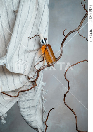Bottle with vitamin serum and white cotton towel on a willow branch, 131263973