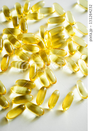 Heap of golden omega 3 capsules close-up on white background with bright light 131264232