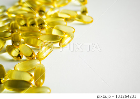 Close-up of shiny golden omega 3 capsules scattered on white background surface Close-up of shiny golden omega 3 capsules scattered on white background surface 131264233