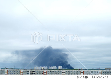 Black smoke billows on background over apartment buildings in modern city. 131265763