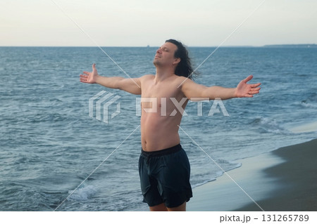 Young man opening arms at beach enjoying freedom sea breeze wind. Young man opening arms at beach enjoying freedom sea breeze wind. 131265789