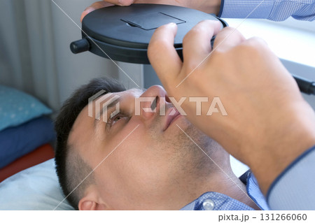 Man looking at mirror on his lashes after eyelash laminating lifting procedure. Man looking at mirror on his lashes after eyelash laminating lifting procedure. 131266060