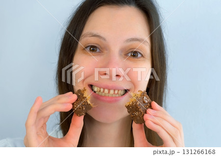 Young woman with yellow bad teeth keeping candy in hands and smiling. Young woman with yellow bad teeth keeping candy in hands and smiling. 131266168