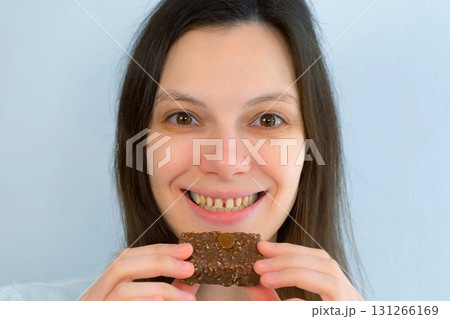 Young woman with yellow bad teeth keeping candy in hands, smelling and smiling. Young woman with yellow bad teeth keeping candy in hands, smelling and smiling. 131266169