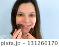 Young woman with yellow bad teeth keeping candys in hands and smiling. 131266170