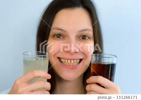 Young woman with yellow bad teeth keeping lemonade in hands and smiling. Young woman with yellow bad teeth keeping lemonade in hands and smiling. 131266171