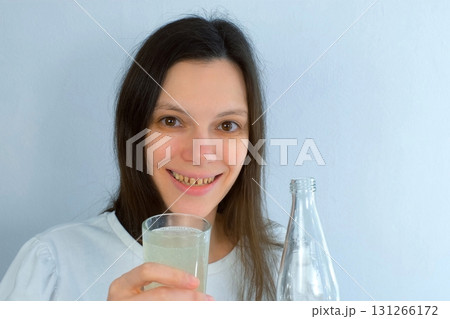 Young woman with yellow bad teeth pouring lemonade in glass and smiling. Young woman with yellow bad teeth pouring lemonade in glass and smiling. 131266172