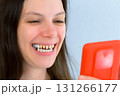 Young smiling woman with yellow bad teeth calling by video on mobile phone. 131266177