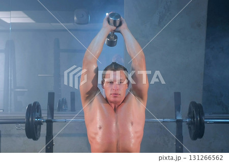 Man bodybuilder training dumbbell triceps extension exercise lifting overhead. Man bodybuilder training dumbbell triceps extension exercise lifting overhead. 131266562