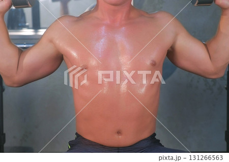 Muscular young man doing shoulders overhead press lifting with dumbbells in gym. Muscular young man doing shoulders overhead press lifting with dumbbells in gym. 131266563
