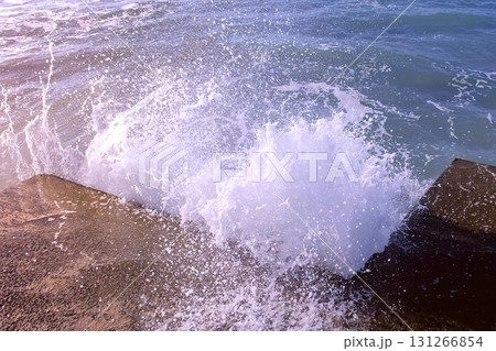 Splashes of water from the stormy waves breaking on the breakwater on waterfront. Side view. 131266854