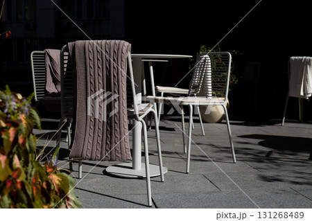 Chic outdoor cafe terrace with modern seating, perfect for business meetings or casual gatherings. Stylish minimalist furniture and cozy blanket set scene for productive and comfortable outdoor work 131268489