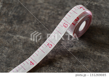 A measuring tape is displayed on a textured dark surface. 131269085