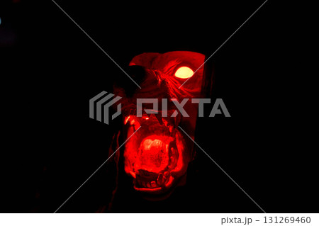 A snarling monster dog head glows bright red in the dark. Fangs, open mouth, and fiery eyes create a scary Halloween display. 131269460