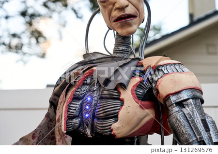Closeup sci-fi cyborg chest with exposed mechanical ribs and blue LED lights. Torn synthetic skin, wires, and tubing create a creepy Halloween prop outdoors. Closeup sci-fi cyborg chest with exposed mechanical ribs and blue LED lights. Torn synthetic skin, wires, and tubing create a creepy Halloween prop outdoors. 131269576