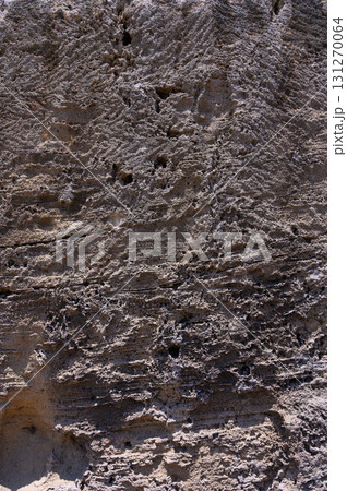 Textured rock surface revealing history with intricate patterns under bright sunlight 131270064