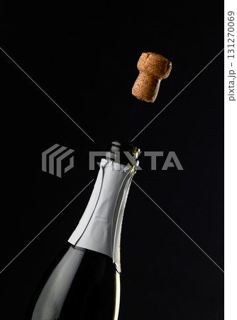Celebration moment as cork pops from bottle of champagne in dramatic low light Celebration moment as cork pops from bottle of champagne in dramatic low light 131270069