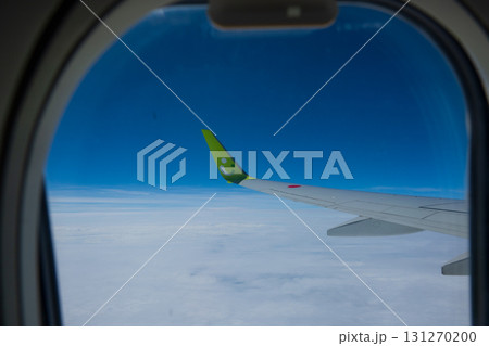 紺色の空と白い雲の間を飛行するジェット機の窓から見た景色 131270200