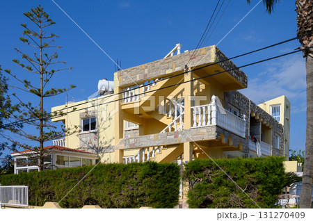Sunny day at a charming Mediterranean villa with lush greenery and vibrant blue skies in late afternoon 131270409