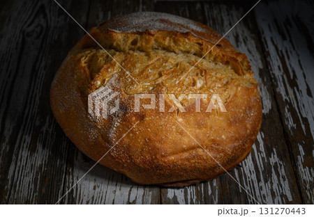 Freshly baked artisanal bread resting on a rustic wooden surface in a cozy Freshly baked artisanal bread resting on a rustic wooden surface in a cozy 131270443