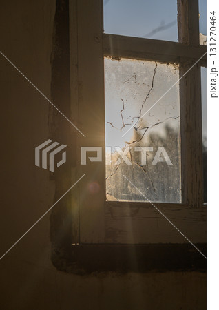 Sunlight filtering through a cracked window in an abandoned building at dusk Sunlight filtering through a cracked window in an abandoned building at dusk 131270464