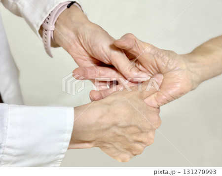 高齢者の手の平を両手でマッサージする女性の手 131270993
