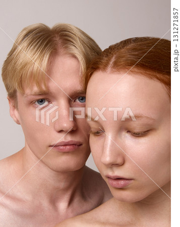 Tender portrait of blond man leaning close to red-haired woman with downcast eyes 131271857