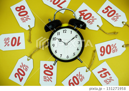 Clock surrounded by various discount tags with percentages like 10%, 20%, 30%, up to 90% off, set against a bright yellow background 131271958