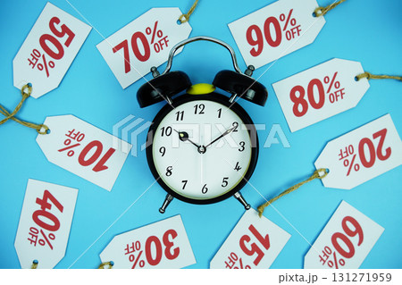 Clock surrounded by various discount tags with percentages like 10%, 20%, 30%, up to 90% off, set against a bright blue background 131271959