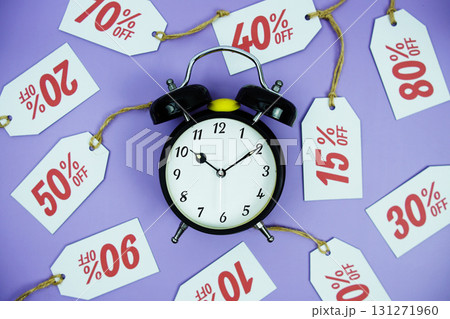 Clock surrounded by various discount tags with percentages like 10%, 20%, 30%, up to 90% off, set against a bright purple background Clock surrounded by various discount tags with percentages like 10%, 20%, 30%, up to 90% off, set against a bright purple background 131271960