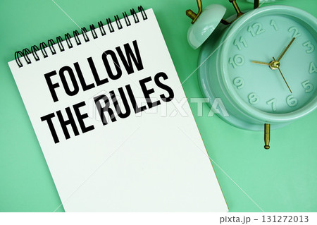 Follow The Rules text with alarm clock flat lay on green background Follow The Rules text with alarm clock flat lay on green background 131272013