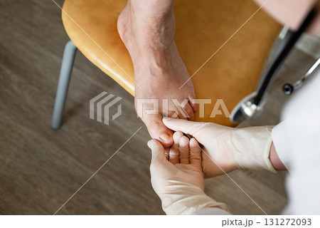 Healthcare professional examines patient's foot in a medical setting during an appointment Healthcare professional examines patient's foot in a medical setting during an appointment 131272093