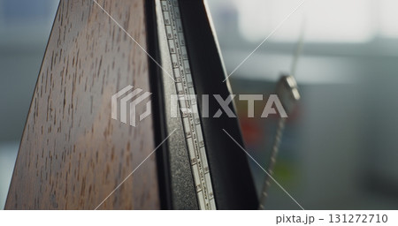 Close Up of Classic Wooden Metronome with Swinging Pendulum 131272710