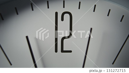 Macro Close Up Shot of Minimalist Wall Clock with Number 12 on Dial, and Running Second and Minute Hands 131272715