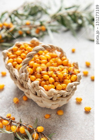 Fresh sea buckthorn berries overflowing a small basket on a textured surface Fresh sea buckthorn berries overflowing a small basket on a textured surface 131273189