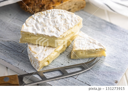 Camembert cheese on cutting board on white table. French cheese with mold on the surface. Camembert cheese on cutting board on white table. French cheese with mold on the surface. 131273915