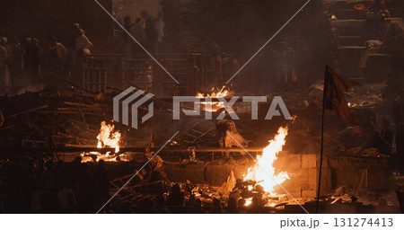 Varanasi, Uttar Pradesh, India. Cremation in process on Manikarnika Ghat. Cinematic Camera movement moving along riverbank embankment. View from riverside. night lights. Fire, smoke - Funeral rites of Varanasi, Uttar Pradesh, India. Cremation in process on Manikarnika Ghat. Cinematic Camera movement moving along riverbank embankment. View from riverside. night lights. Fire, smoke - Funeral rites of 131274413