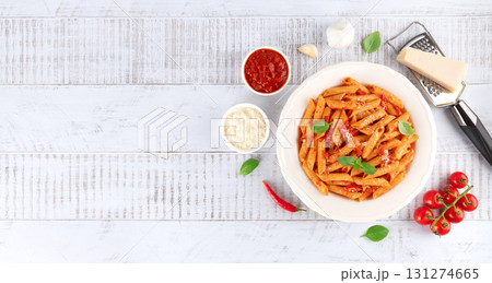Pasta arrabbiata with tomato sauce, chili, parmesan and basil on wooden background. IItalian cuisine 131274665