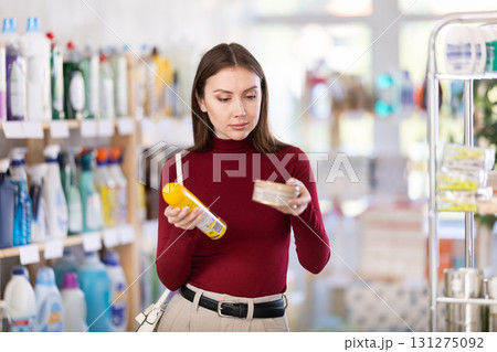 Young woman chooses floor and wood cleaner in store 131275092