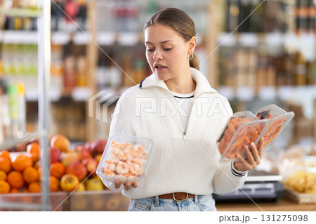 Girl chooses tasty prawns to buy in grocery department section of store Girl chooses tasty prawns to buy in grocery department section of store 131275098