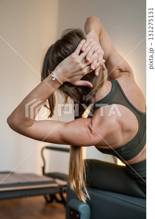 Woman doing Pilates exercise for core and back muscles on Reformer machine with determination and focus on strength body 131275131