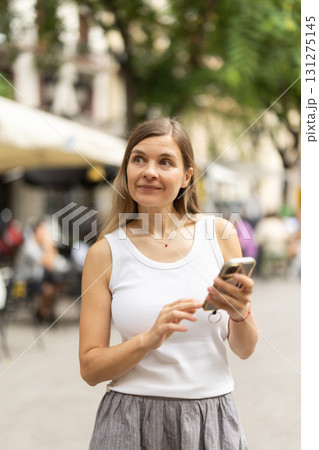 Female pedestrian with phone in summer European capital Female pedestrian with phone in summer European capital 131275145